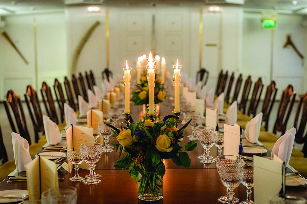 The candlelit State Dining Room set for dinner with floral displays.